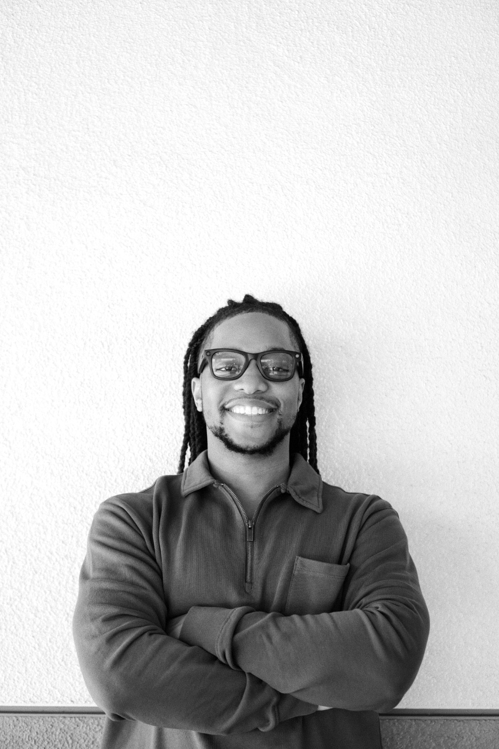 Portrait of Anthony Foster, smiling with arms crossed, in black and white
